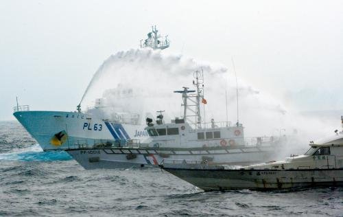 台湾“海巡署”的巡逻船（中）在掩护保钓船“全家福”号（右）躲避日本海上保安厅巡视船的水炮攻击。