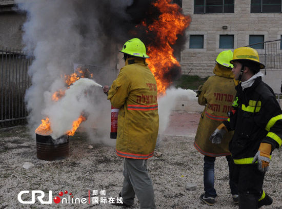 两名志愿者在消防员的指挥下灭火。（摄影：张瑾） 