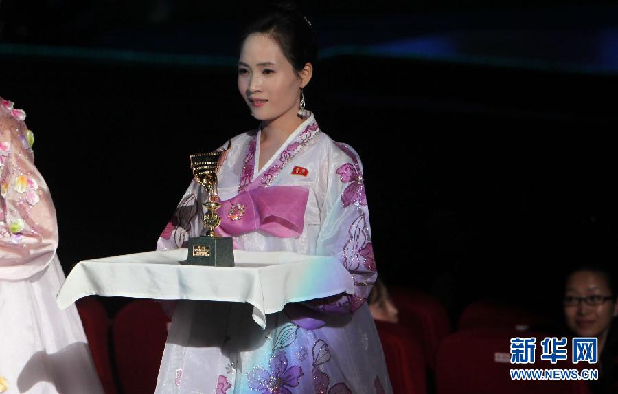 9月17日,在朝鲜首都平壤,一名朝鲜礼仪小姐展示"火炬奖"奖杯.